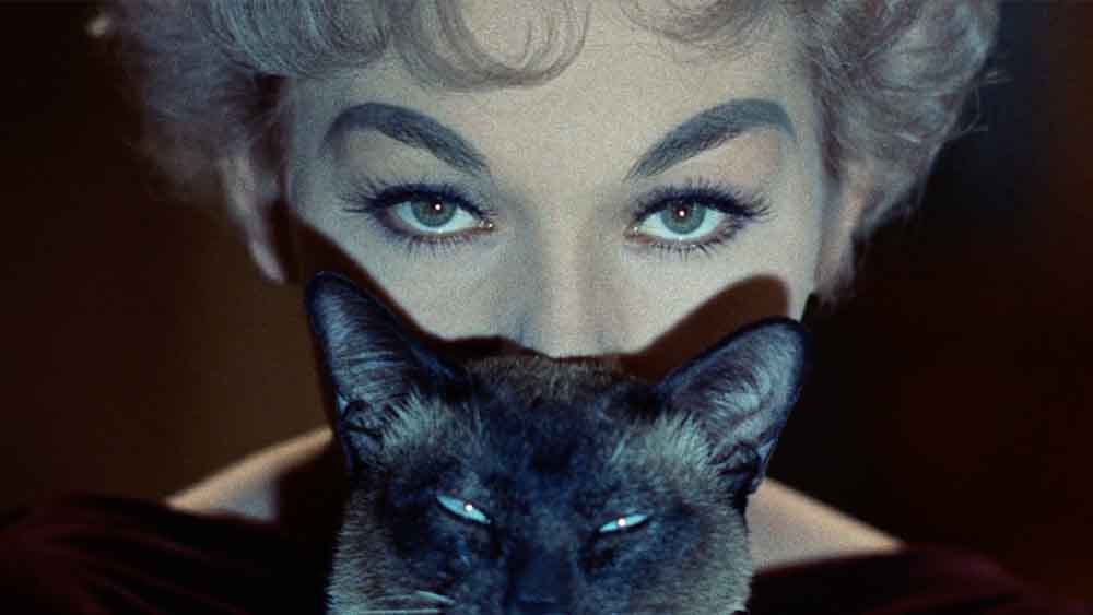 A closeup of Kim Novak's face, eclipsed by the face of her Siamese cat, in Bell, Book and Candle