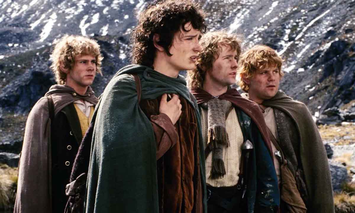 A photo from The Fellowship of the Ring, featuring four hobbits standing together in the mountains