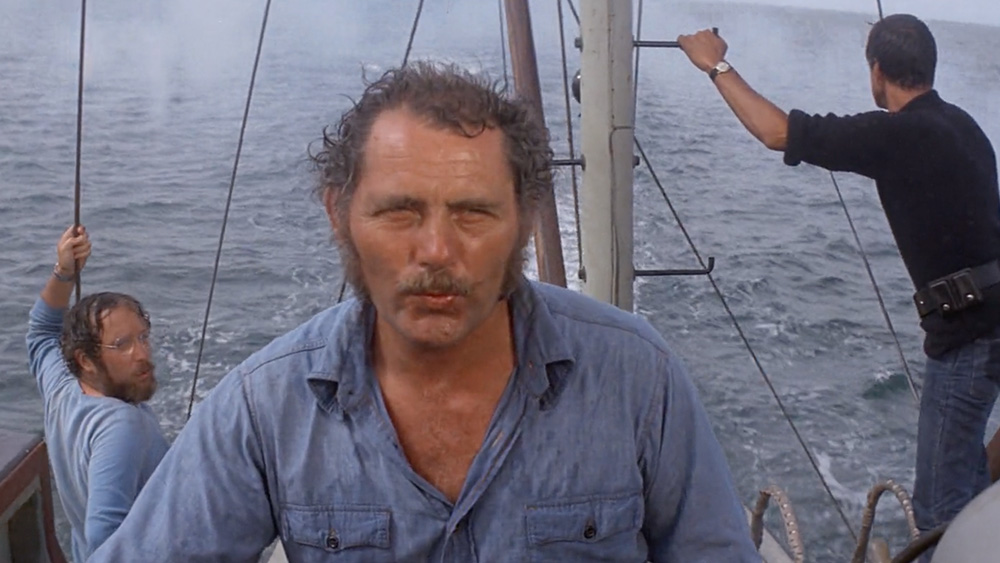 Robert Shaw whistles as he captains his vessel with Roy Scheider and Richard Dreyfuss look on.